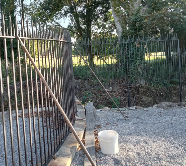 The fence is bolted to the small wall and strengthen by uprights.